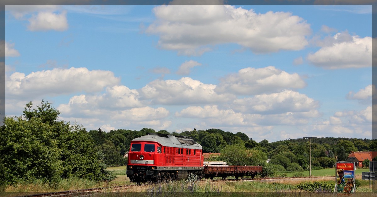 232 469 mit ihrem grenzlastigen Zug in Klein Plasten am Bahnübergang in Richtung Kargow (Meckl.) aus Möllenhagen kommend am 30.06.2015
